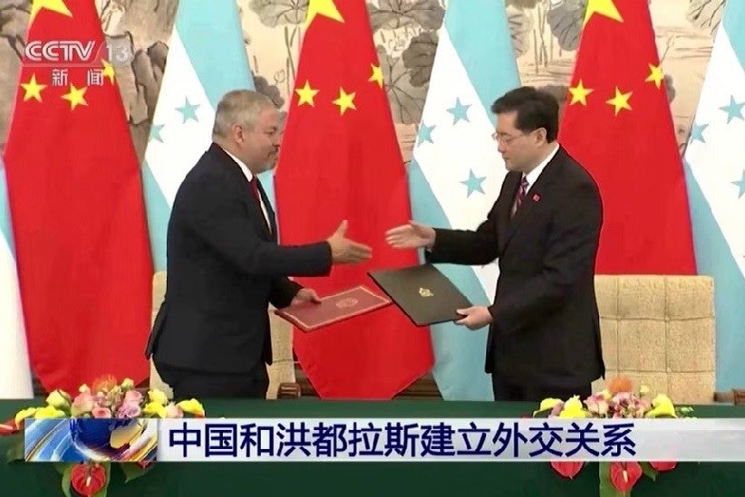 Los cancilleres de Honduras, Eduardo Enrique Reina García, a la izquierda, y el de China, Qin Gang, intercambian acuerdos durante una ceremonia de firma en Beijing, el 26 de marzo de 2023. (CCTV a través de AP)