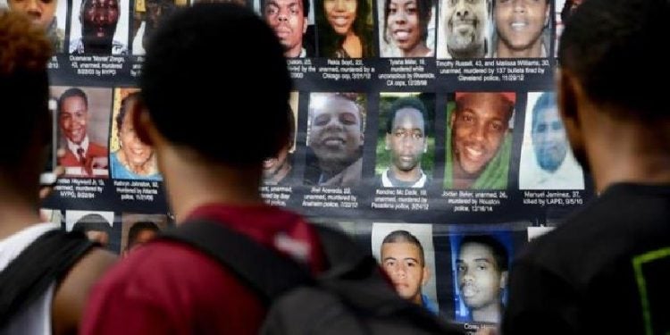 Em protesto após um ano da morte de Michael Brown, manifestantes estendem cartaz com foto de pessoas que foram mortas pela política