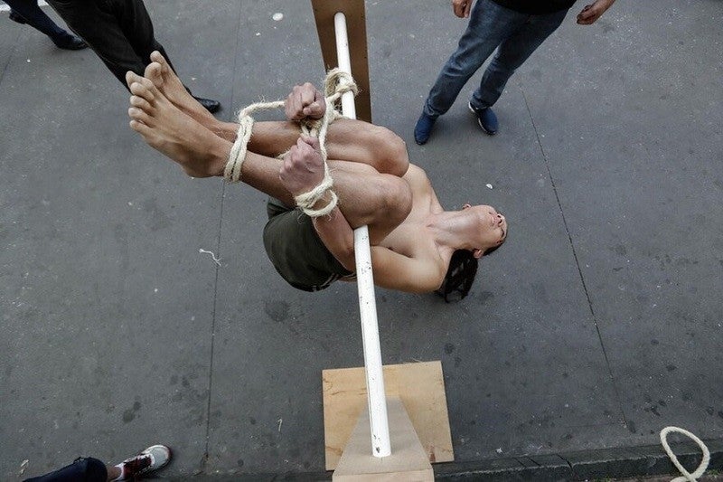 Voluntário demonstra um método de tortura conhecido como 'Pau de Arara' durante manifestação em memória dos mortos, torturados e desaparecidos durante a ditadura militar no Brasil (1964 - 1985), em frente ao Museu de Arte de São Paulo (MASP), 1° de abril