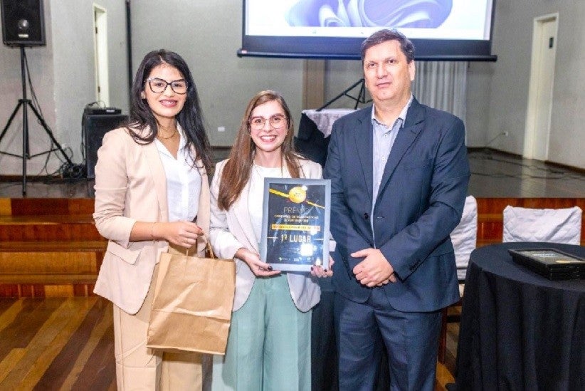 Amabily Fruttos e Rafaela Buono, técnicas do Observatório Social em Foz do Iguaçu, recebem o prêmio do presidente da Rede OSB, Jean Pedroso – foto: Divulgação/OSB